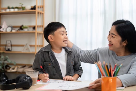 A mother and her son enjoy quality time together as they engage in drawing and art activities. The mother encourages her son, creating a supportive and fun environment for learning.