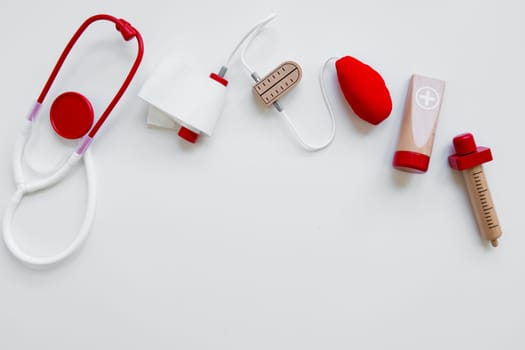 Children medical toy set on white background featuring stethoscope and syringe.