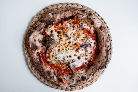 Delicious neapolitan pizza with mozzarella and tomato on woven placemat.