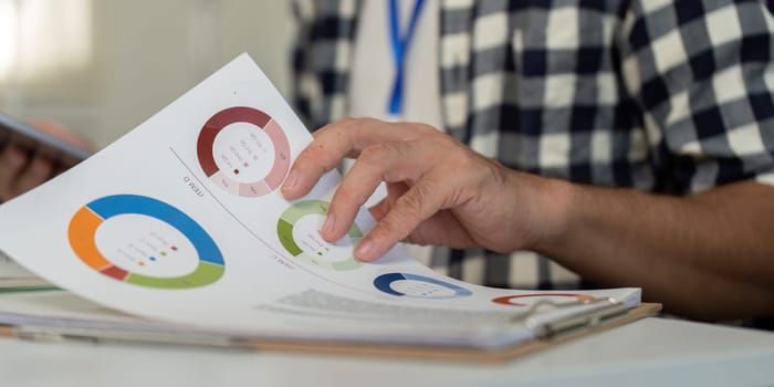 An individual reviewing colorful charts and graphs during a business analysis session in a well-lit, modern office environment.