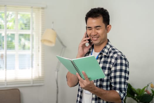 A smiling professional talking on the phone while studying a notebook, reflecting a positive atmosphere in a modern office with plants.