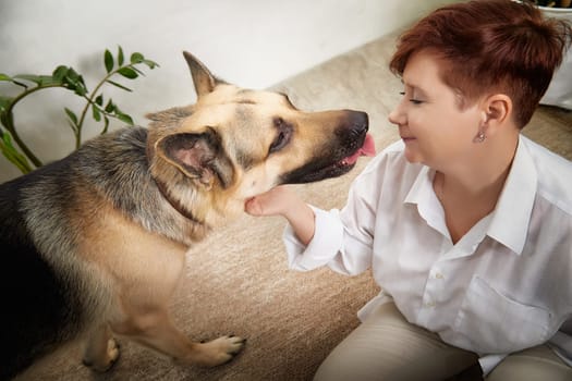 Middle-aged woman plays with her German Shepherd dog in a warm and inviting room, showcasing their bond and joy.