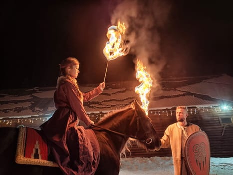 Actors dressed in Viking costumes perform a captivating fire show on a winter night, creating an enchanting atmosphere.