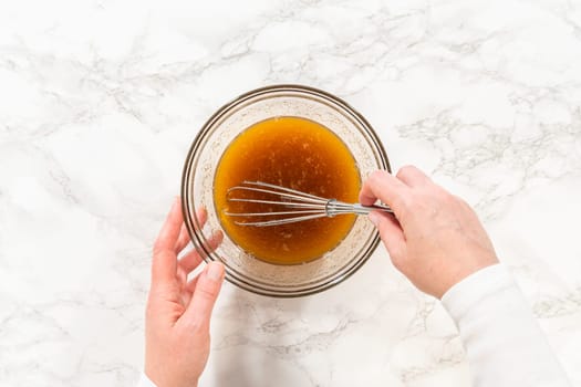 Top view of eggs and maple syrup in a small mixing bowl for Amber Gingerbread Cookie Dough, capturing the liquid ingredients before mixing. The maple syrup adds a warm, rich flavor and color to the gingerbread dough.