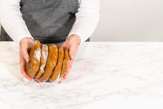 Eye-level view of hands holding multiple wrapped discs of Classic Gingerbread Cookie Dough, ready to be chilled for later use. The dough discs are stacked and wrapped in plastic, ensuring they stay fresh for baking.