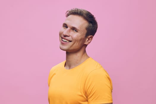 Portrait of a smiling man with short brown hair and a vibrant yellow t-shirt, standing in front of a pink background. Bright, cheerful, and casual mood perfect for health, happiness, and lifestyle concepts.