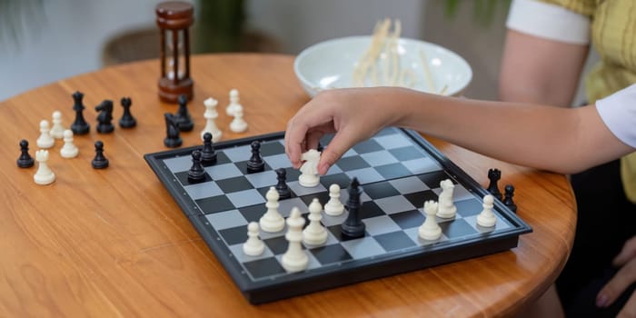 A mother and her son enjoy a fun game of chess together, sharing laughter and bonding over strategy in their cozy living room.