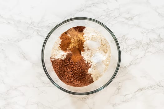 A mixing bowl containing flour, cocoa powder, and spices for Chocolate Gingerbread Cookie Dough. This combination of dry ingredients adds depth and warmth to the holiday cookie flavor.
