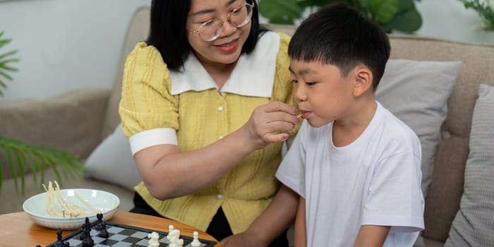 A mother and her son enjoy a fun game of chess together, sharing laughter and bonding over strategy in their cozy living room.