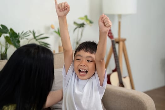 A mother and son joyfully celebrating after winning a chess game, emphasizing happiness and connection at home.