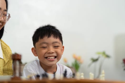 A mother and son sharing a joyful moment while playing chess at home, highlighting love and connection.
