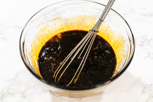 A bowl filled with molasses and two large eggs for Spiced Gingerbread Cookie Dough Perfect for Baking. The dark molasses contrasts with the bright yolks, creating a rich base for the dough.