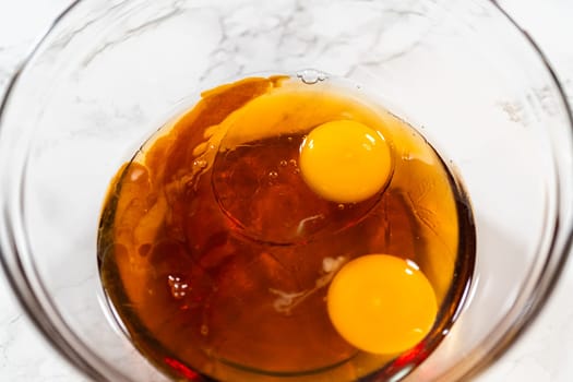 Wet ingredients including maple syrup and two eggs in a glass bowl for Pale Gingerbread Cookies. Ready for mixing.