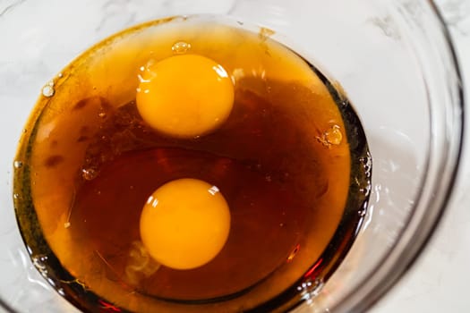 Two large eggs cracked into a glass bowl, combined with molasses. This mixture adds richness, moisture, and depth of flavor to the Classic Red Gingerbread Dough.