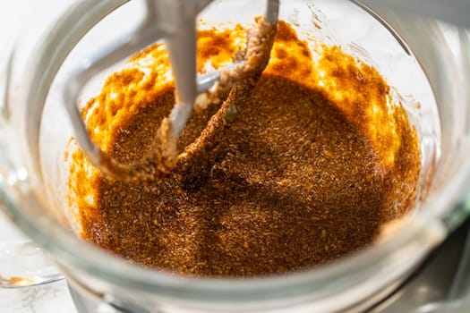 Molasses mixture blending with butter and sugar in a stand mixer for Zesty Orange Gingerbread Cookie Dough. The rich, dark molasses combines smoothly with the creamed ingredients, adding depth to the dough.
