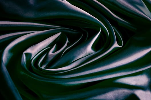 Top view of polished dark grey silk cloth with silky sheen and beautiful natural draping. Suitable for design and wallpaper background.
