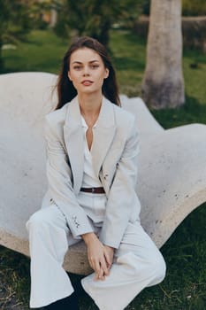 This professional woman exudes confidence in her stylish business attire, blending a contemporary look with nature. The soft colors and relaxed pose emphasize her approachability and professionalism.