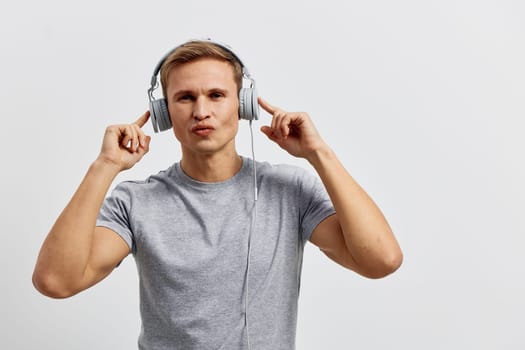 young caucasian man wearing headphones working with music listen and enjoy digital nomad lifestyle casual gray t-shirt isolated on plain white background technology and remote work concept