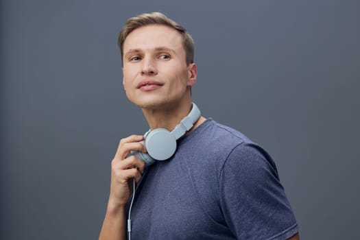 thoughtful man with headphones around neck wearing blue t-shirt looking up on grey background isolated studio portrait digital nomad technology wireless communication concept