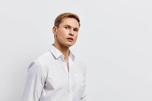 Distinguished man with light brown hair dressed in a white shirt, posing with a serious expression against a plain white background in a studio setting. Concept: professionalism and confidence