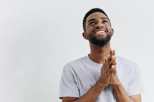 Joyful young man in casual attire energetically clapping hands, celebrating success and radiating positive vibes against a white background.