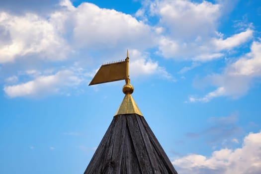 Golden flag finial on wooden tower against sky background