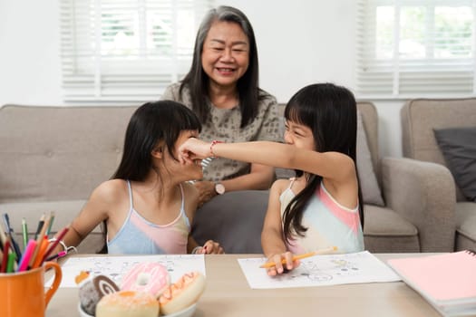 The grandmother and her granddaughters laugh together as they engage in a playful drawing session, creating cherished memories through art.