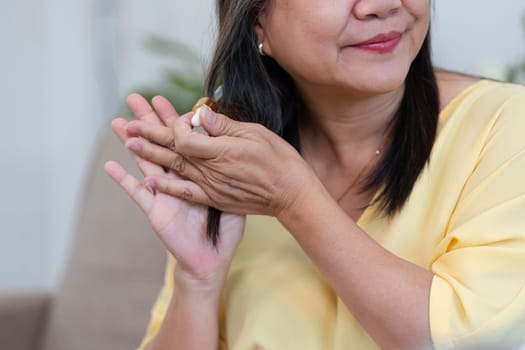 An older woman applies hair serum to nourish and enhance her hair's beauty, reflecting the importance of hair care in a self-care routine.