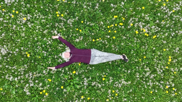 Drone shot of a woman lying relaxed in a dandelion meadow