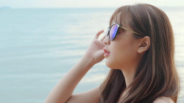 Beautiful Asian woman wearing sunglasses at tropical paradise beach and smiling, Happy female in bikini swimsuit having fun eyewear in holidays summer vacation travel