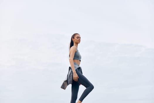 A young woman in stylish athletic wear exercises outdoors, exhibiting confidence and an active lifestyle Ideal for healthy living and fitness related themes