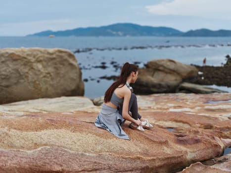 A young Asian woman in athletic clothing sits on the coastline, connecting with nature and introspection The tranquil ocean backdrop enhances the peaceful mood