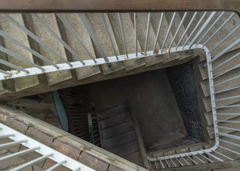 Newcastle, UK - Apr 14, 2025 - View from above of concrete spiral staircases pattern with steel handrail into Basement of the historic building architecture. use it as your Wallpaper, Poster and Copy space, Selective focus.