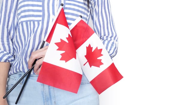 Unrecognized girl student in white blue shirt holding small Canadian flag over gray background, Canada day, holiday, vote, immigration, tax, copy space.