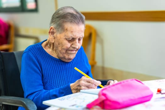 Senior woman enjoying creative time, drawing with colored pencils in a nursing home, showcasing a fulfilling and engaging activity