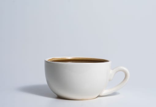 Minimalistic image of a white ceramic cup filled with espresso coffee, placed on a light surface with soft shadows and a clean background.