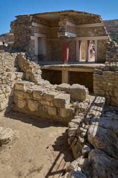 Crete.Greece - april 26, 2025: Tourists exploring the historic site of Knossos Palace, featuring well-preserved ruins, vibrant red columns, and ancient Minoan architectural details under a sunny sky.