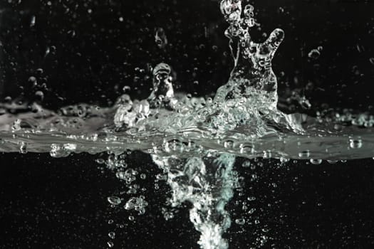 Water splashing as it's poured into aquarium tank, black background