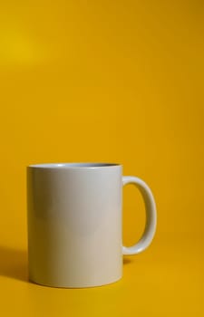 Minimalist white coffee mug placed on a bold yellow background with space for text or branding.