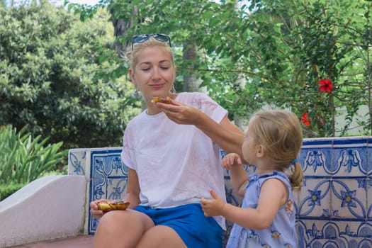 Mother and daughter eating Pasteis de Belem egg tart. Azulejos tile on a background