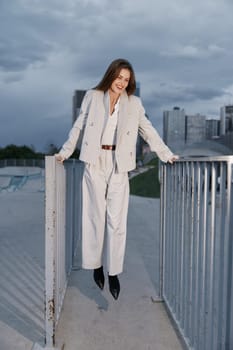 smiling woman in beige suit outdoors with urban background showing confidence and professionalism in business style against cloudy autumn sky