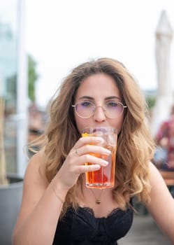 relaxed young woman with glasses drinking alcohol