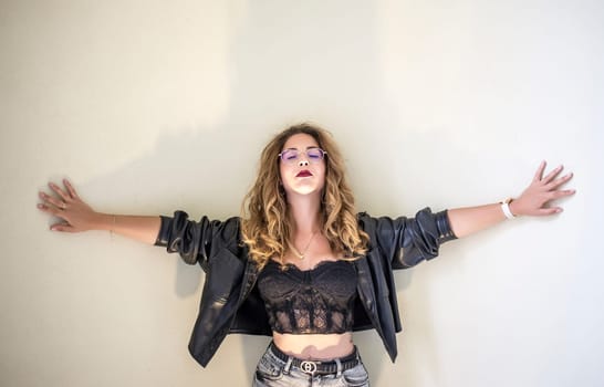 thoughtful young woman stands in front of a wall