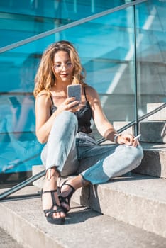 relaxed young woman with smartphone and cigarette in the city