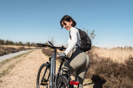 Free-spirited woman with backpack jumps on her bike in the great outdoors, capturing the essence of adventure and healthy living.