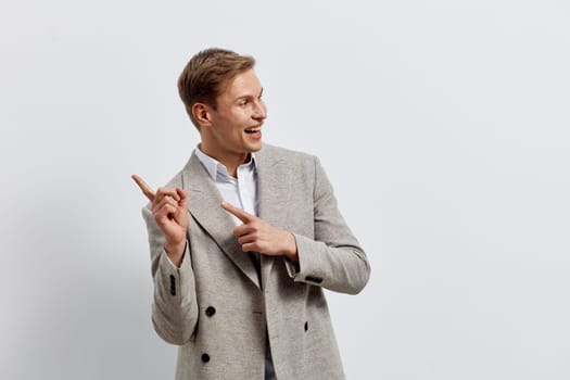 Confident young man dressed in smart casual attire laughs and points finger, expressing enthusiasm and positivity. Neutral background emphasizes cheerful mood, suitable for business or personal success themes.