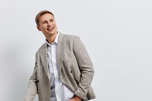 smiling young caucasian man wearing casual jacket looking aside with happy and cheerful expression isolated on plain light background, symbolizing digital nomad lifestyle and remote work freedom. Concept: digital nomad