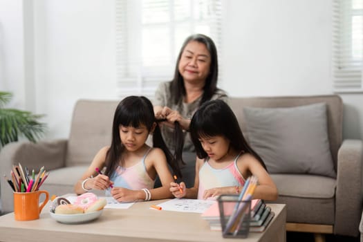 A heartwarming scene of a grandmother helping her granddaughters with their drawing, encouraging creativity and family interaction.