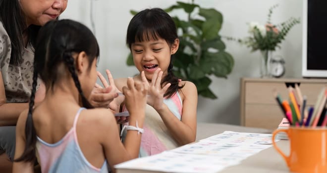 A joyful learning moment as a grandmother and her granddaughters share laughter while engaging in educational activities at home.