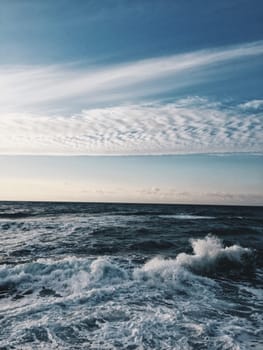 Blue sea wave with white foam and sky in background